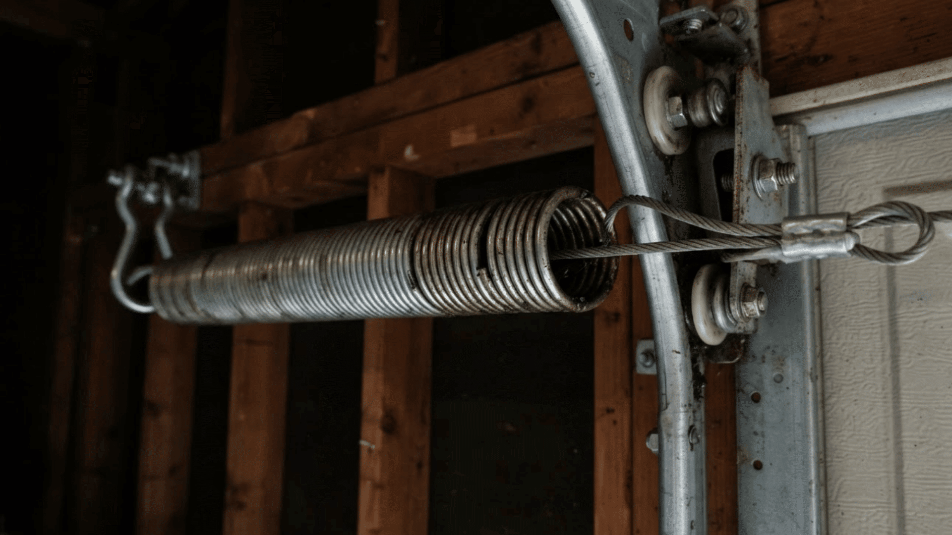 extension spring safety cable running through a garage door spring beside the metal tracks