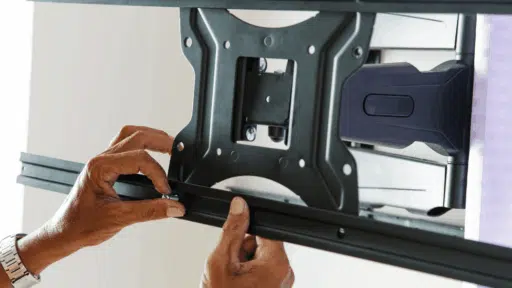 hands tightening the lower rail of a television wall bracket