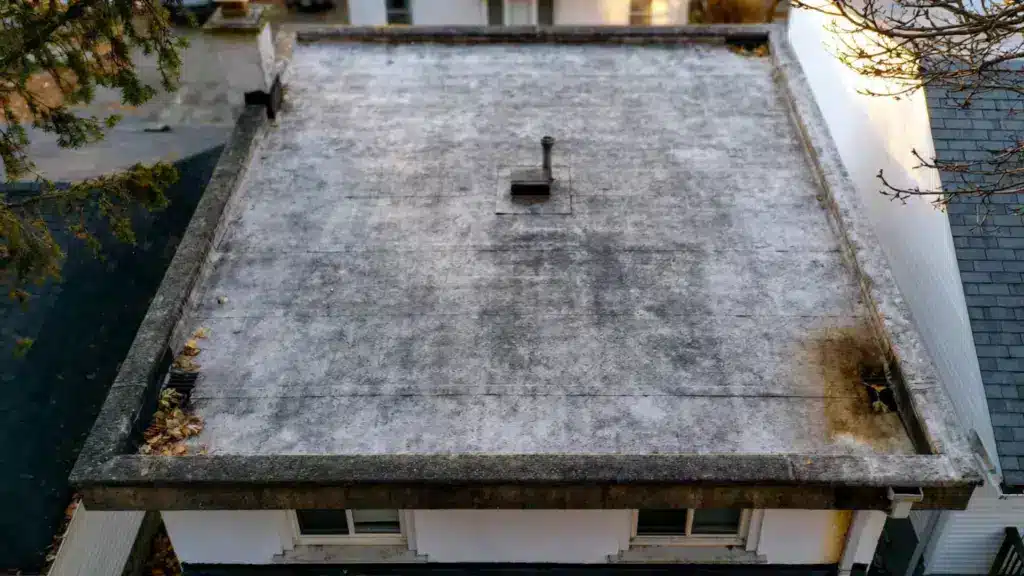 aged flat roof with visible wear, drainage areas, and surface maintenance concerns