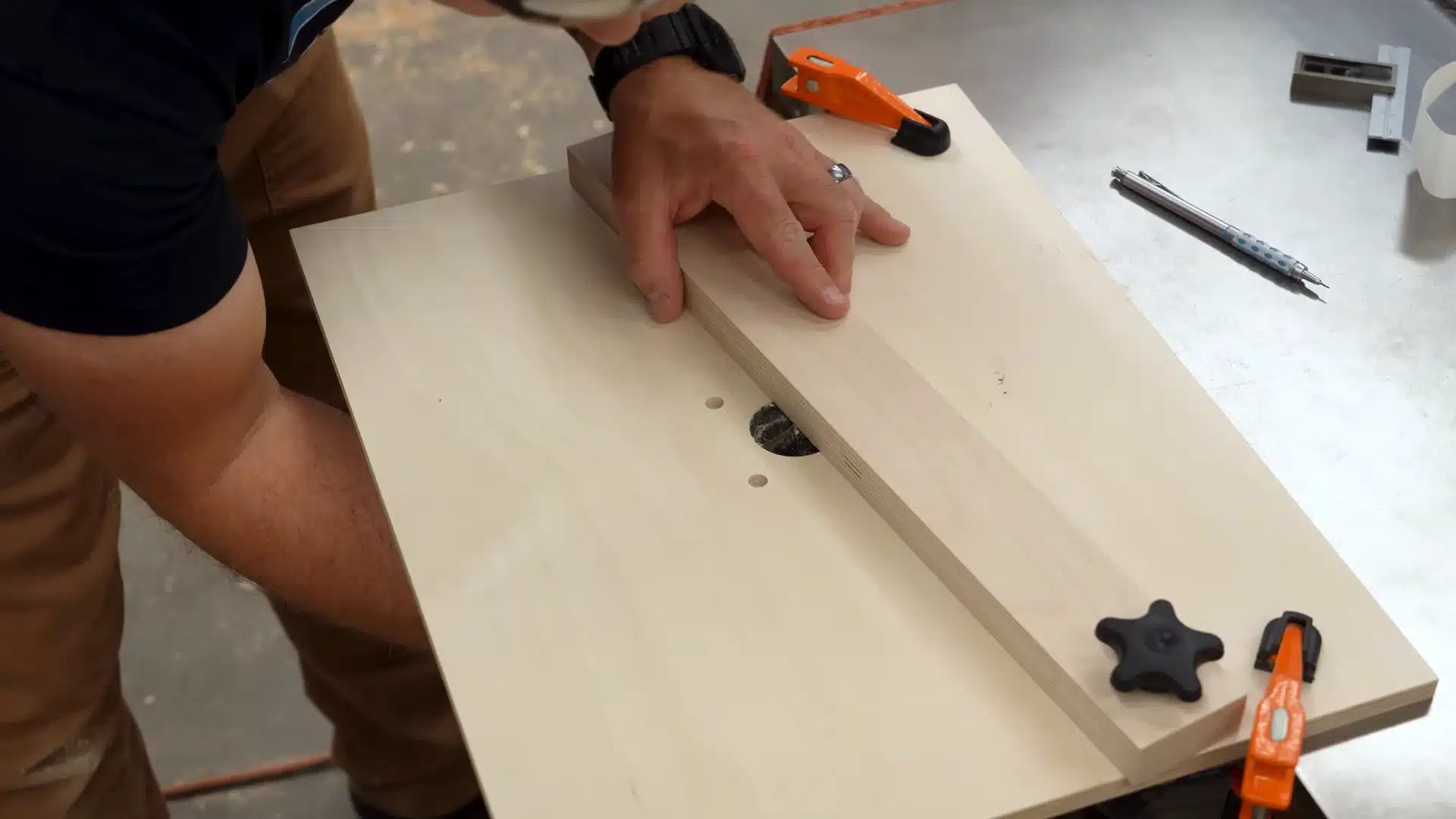 hand pressing wood board over router table hole