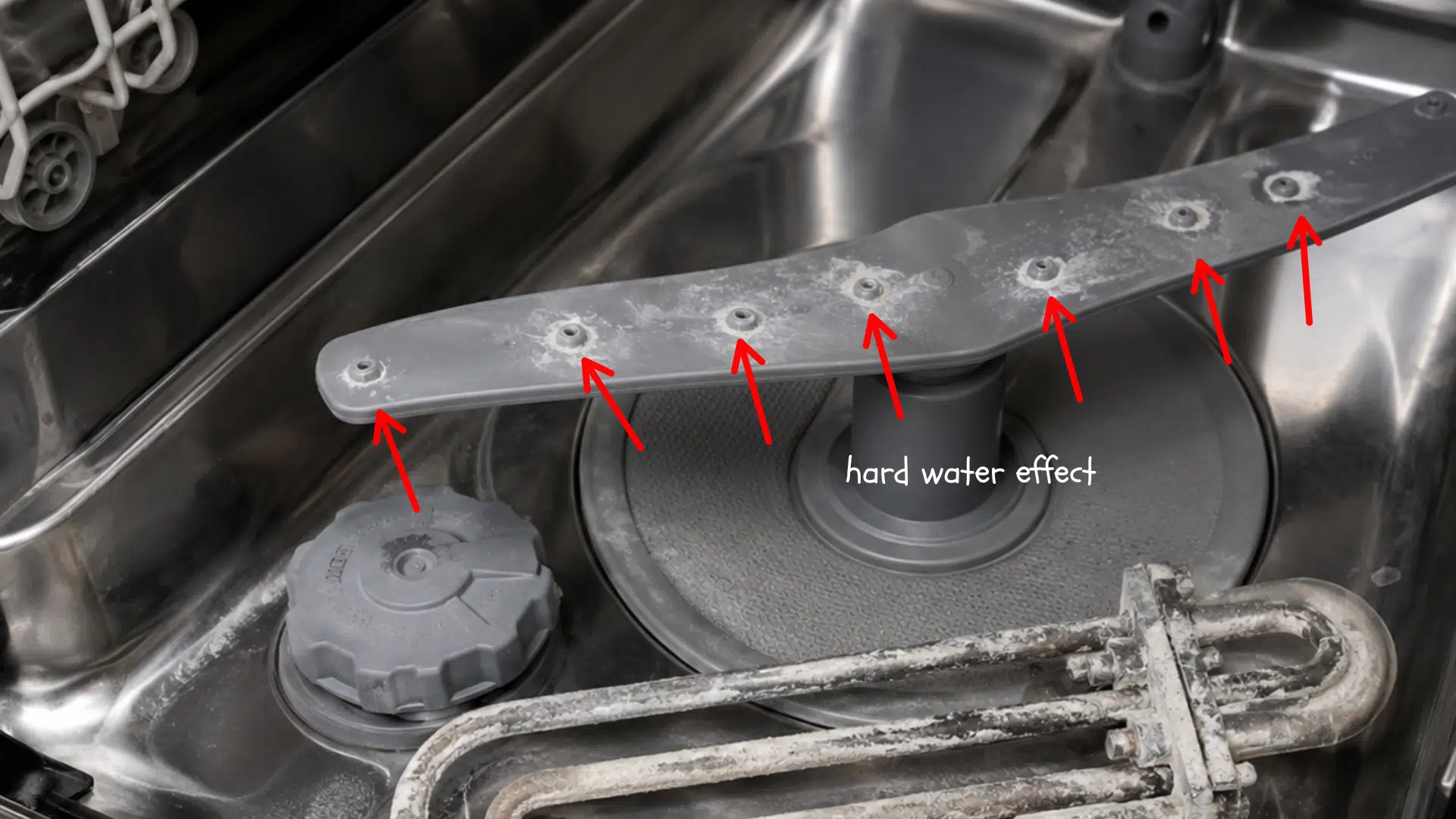 chalky mineral buildup coating dishwasher spray holes and the exposed heating element in the basin