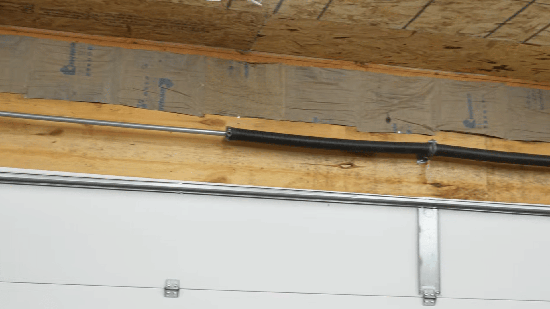 homeowner installing fiberglass batt insulation between ceiling joists in an unfinished garage