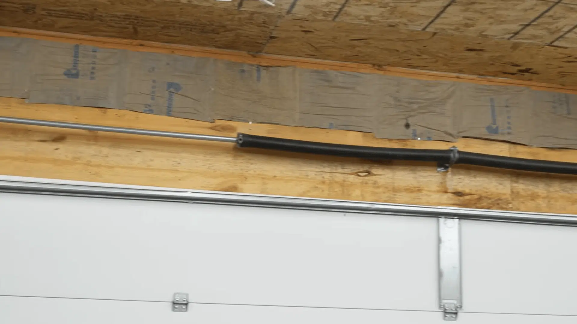 homeowner installing fiberglass batt insulation between ceiling joists in an unfinished garage