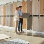 Couple examining wood flooring samples in a well-lit showroom with large windows