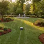 Lush garden with robotic lawnmower and Adirondack chairs on gravel patio in the background