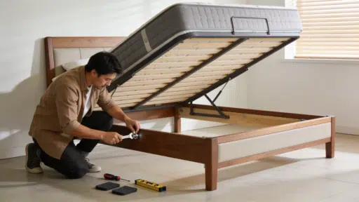 person tightening a corner bolt on a wooden bed frame to stop it squeaking