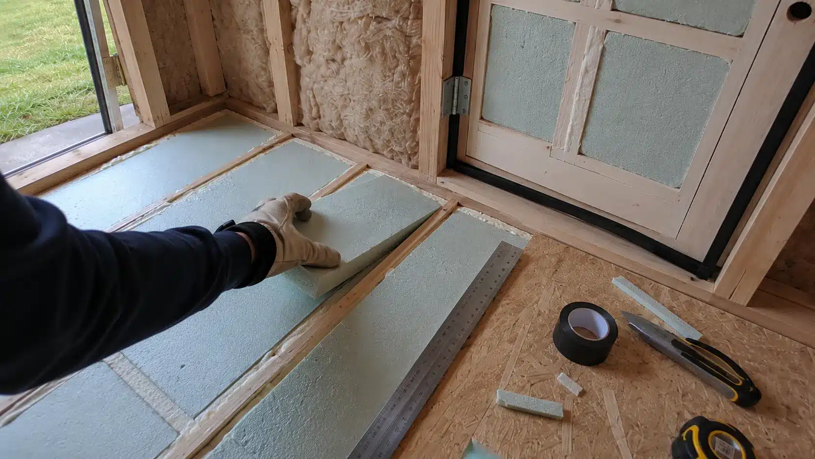 fitting rigid foam insulation into the shed floor near an insulated door