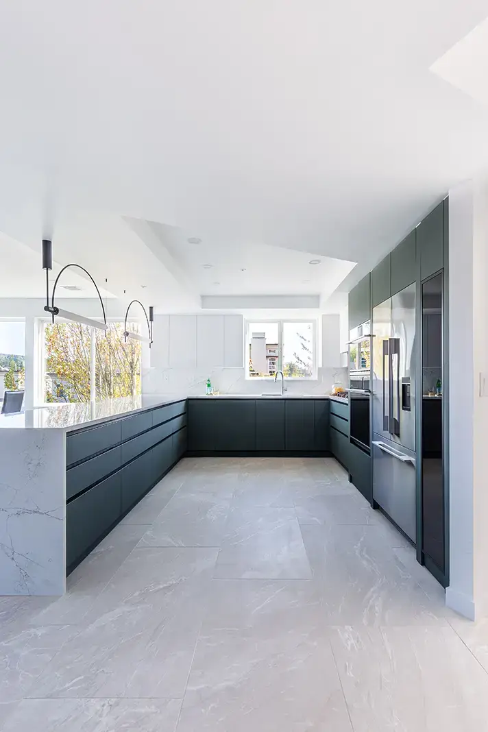 Modern kitchen with dark cabinetry, stainless steel appliances, and marble countertops under bright natural light