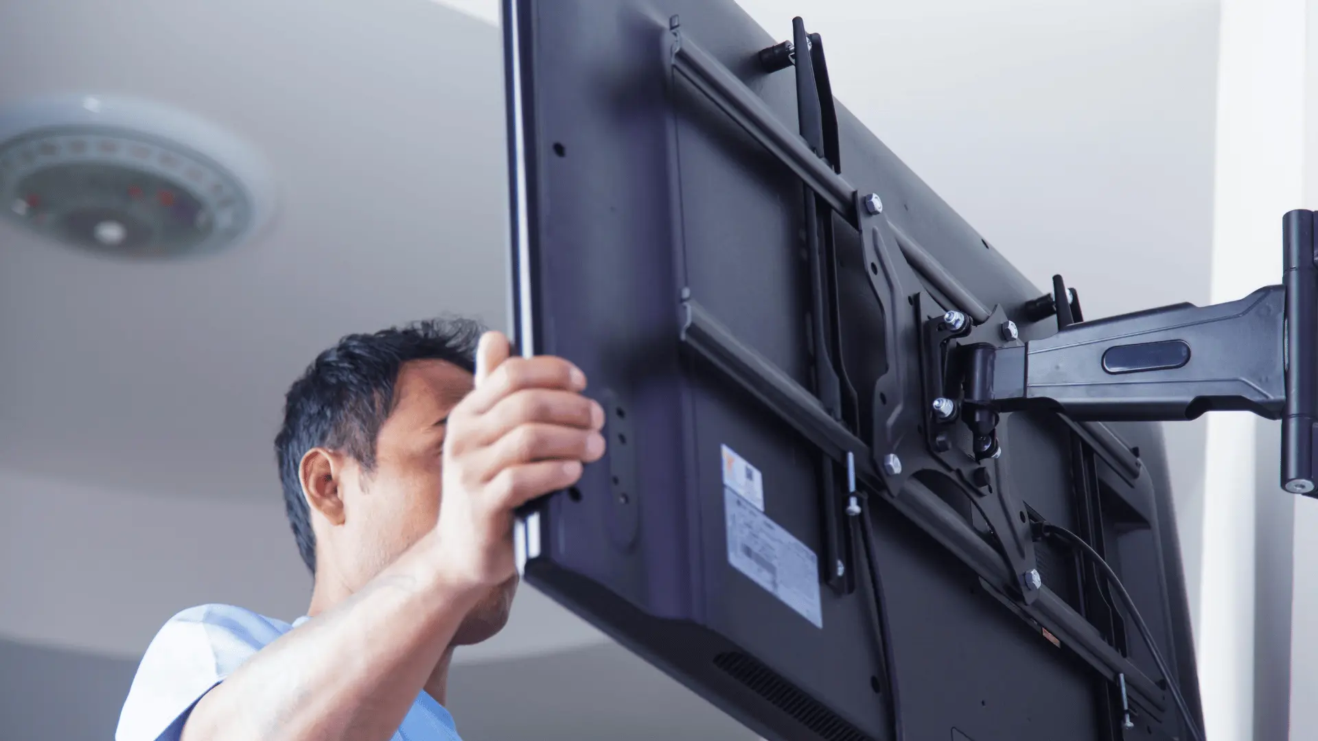 person securing a television onto an extended wall mount