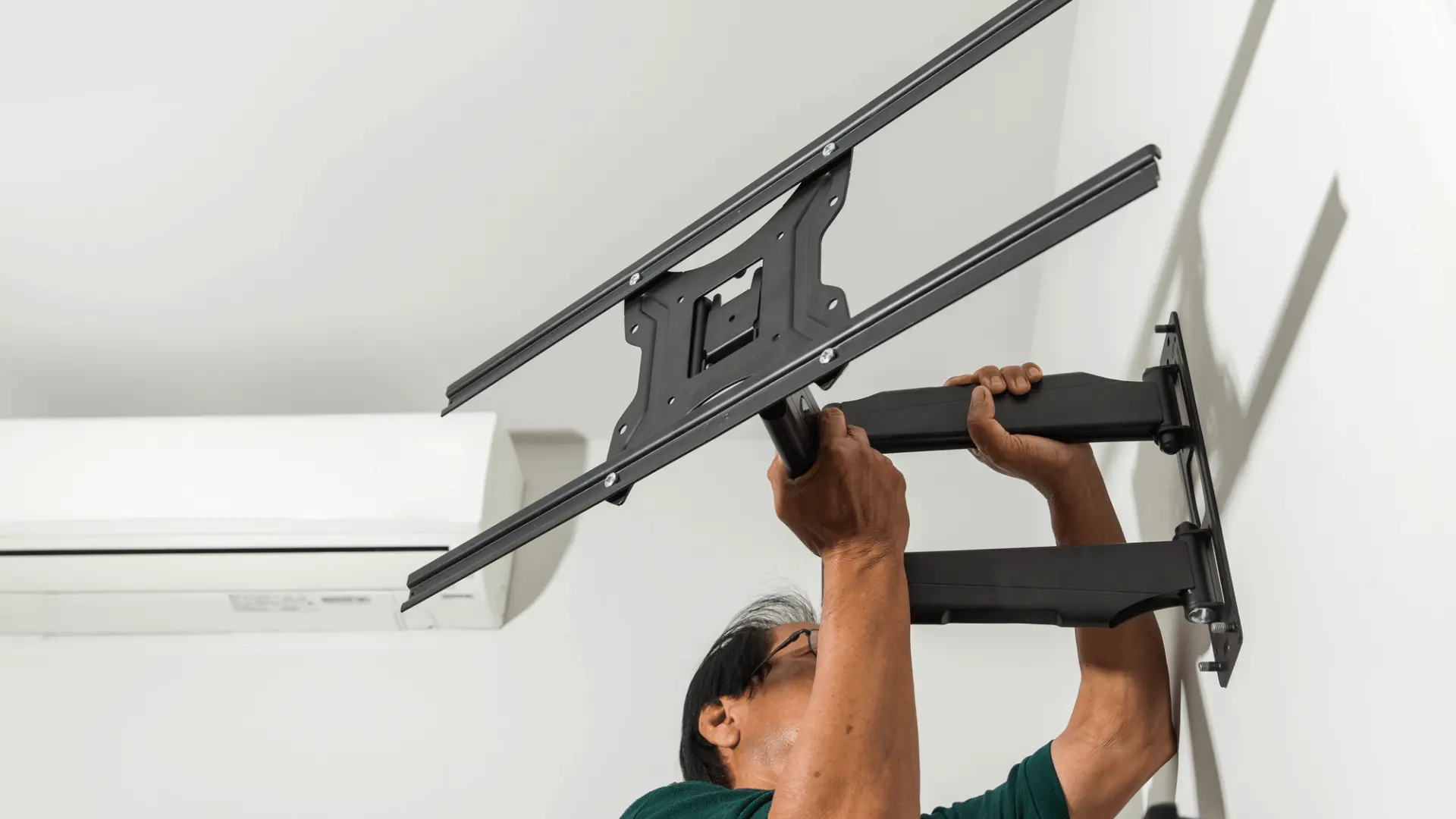 installer lifting a full motion tv bracket into position