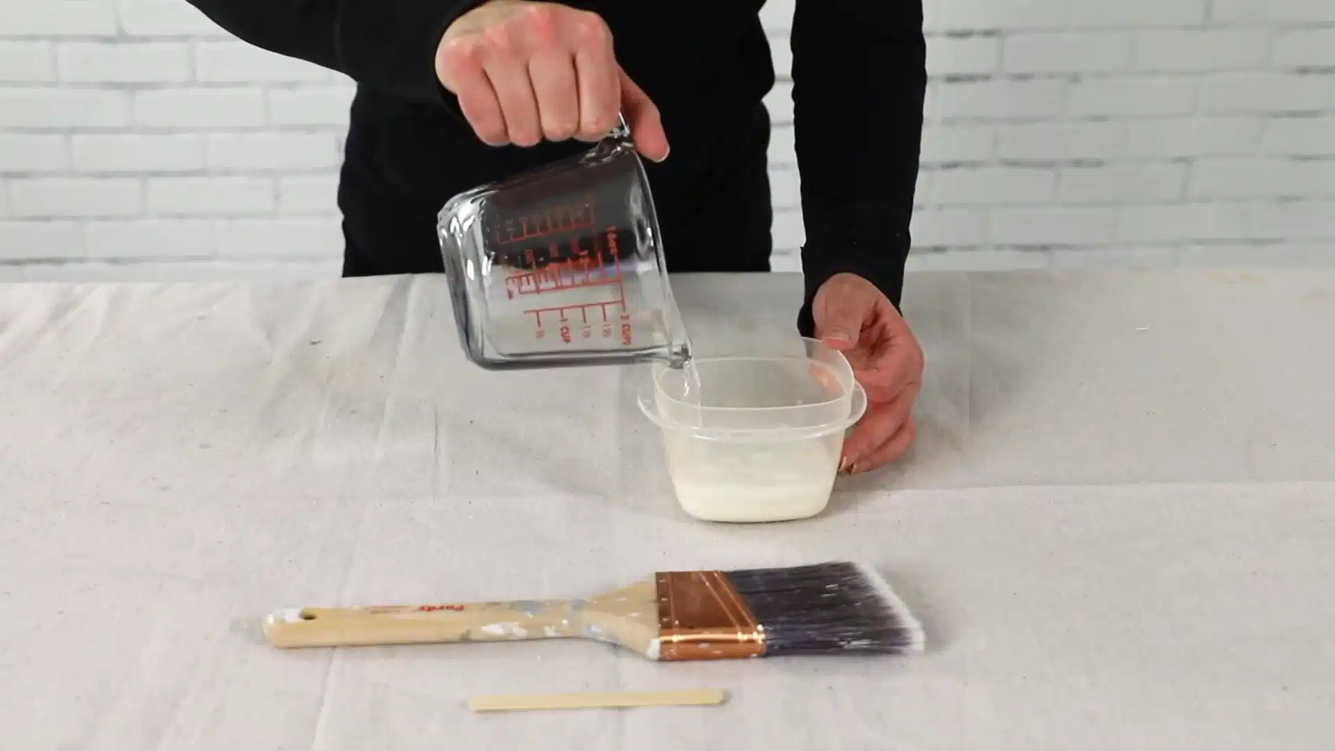 pouring water into paint to mix white wash solution