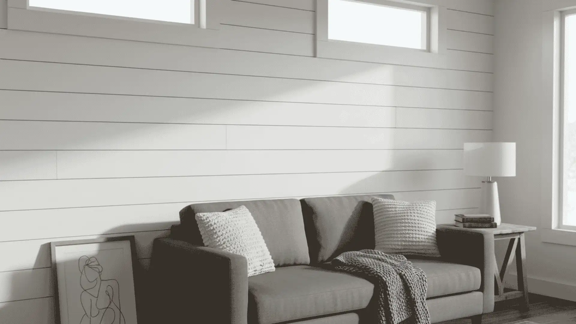 white shiplap living room wall behind gray sofa with pillows lamp windows and soft sunlight