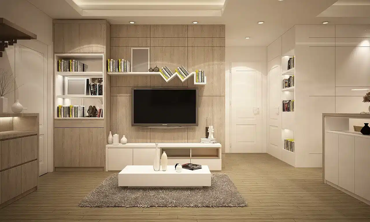 Modern living room with beige wood paneling, wall-mounted TV, shelving, and white coffee table on rug