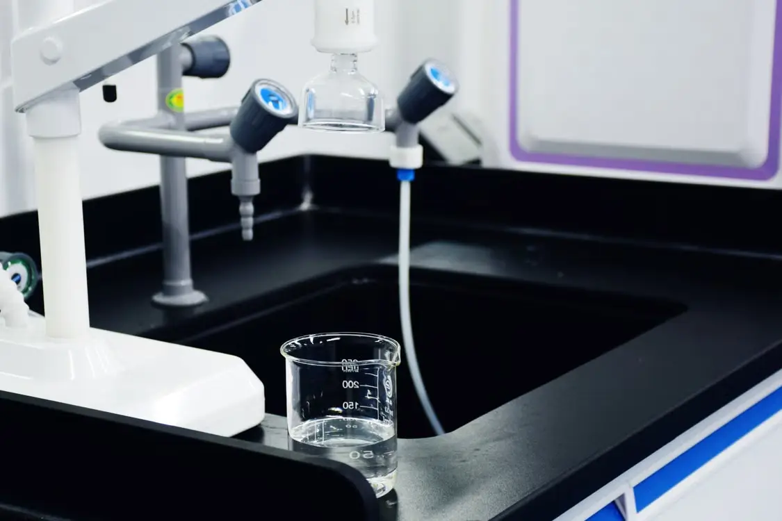 Laboratory sink with glass beaker and scientific equipment on black countertop