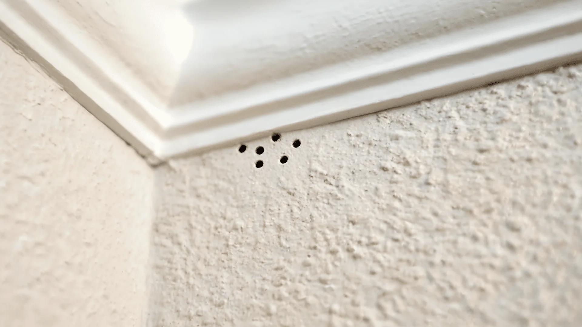 tiny pinholes in painted drywall near the ceiling