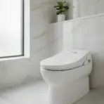 Modern white toilet in bright marble-tiled bathroom with frosted window and small potted plant