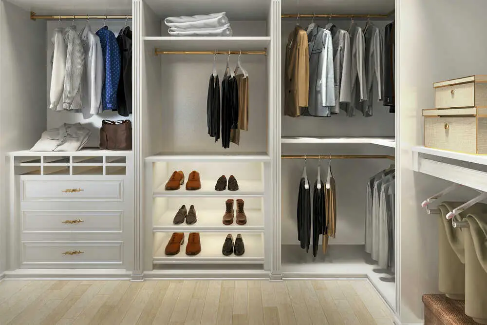 Organized walk-in closet with neatly arranged clothes, shoes, and storage boxes on wooden floor