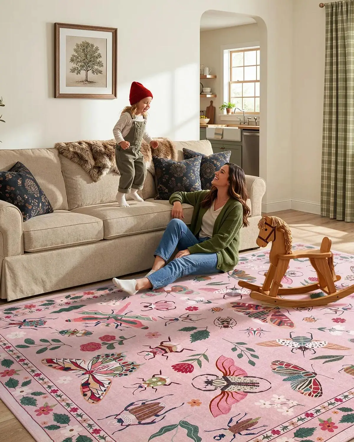 Child wearing a red hat jumping on beige couch with woman seated on floral pink rug
