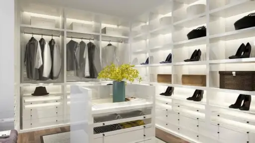 Modern walk-in closet with white shelving, clothing, and shoes, featuring a centered island and yellow flowers