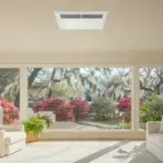 Bright living room with cream sofas and large window overlooking blooming garden and trees
