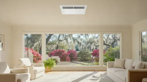 Bright living room with cream sofas and large window overlooking blooming garden and trees