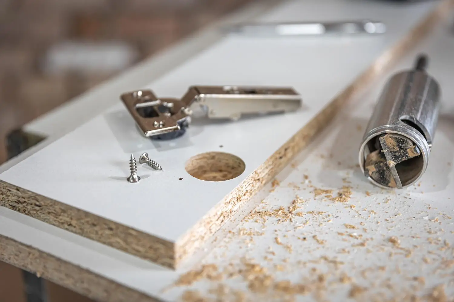 Woodworking tools and screws on particle board with sawdust in a workshop setting