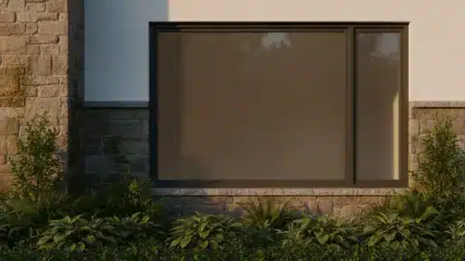 Large frosted window in stone wall with surrounding greenery in sunlight