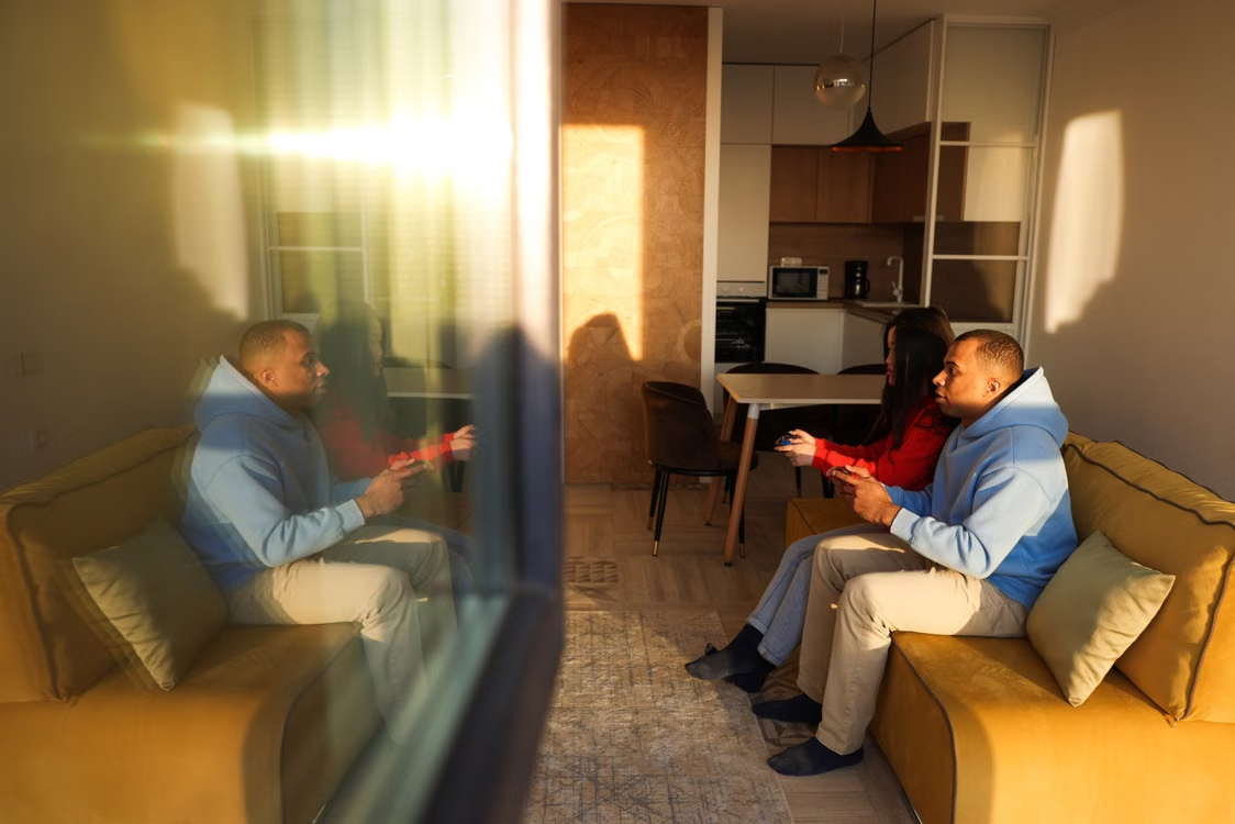 A couple enjoys playing video games together on a sofa in a cozy living room setting.
