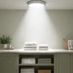 Laundry room with stacked towels, green cabinets, and natural light from ceiling fixture