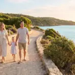 Family walking on scenic coastal path by the beach with lush greenery and ocean view