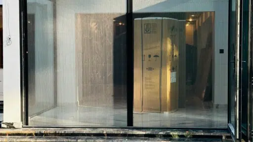 Modern glass-walled room with shipping crate reflected in clear swimming pool