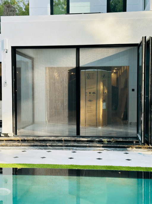 Modern glass-walled room with shipping crate reflected in clear swimming pool