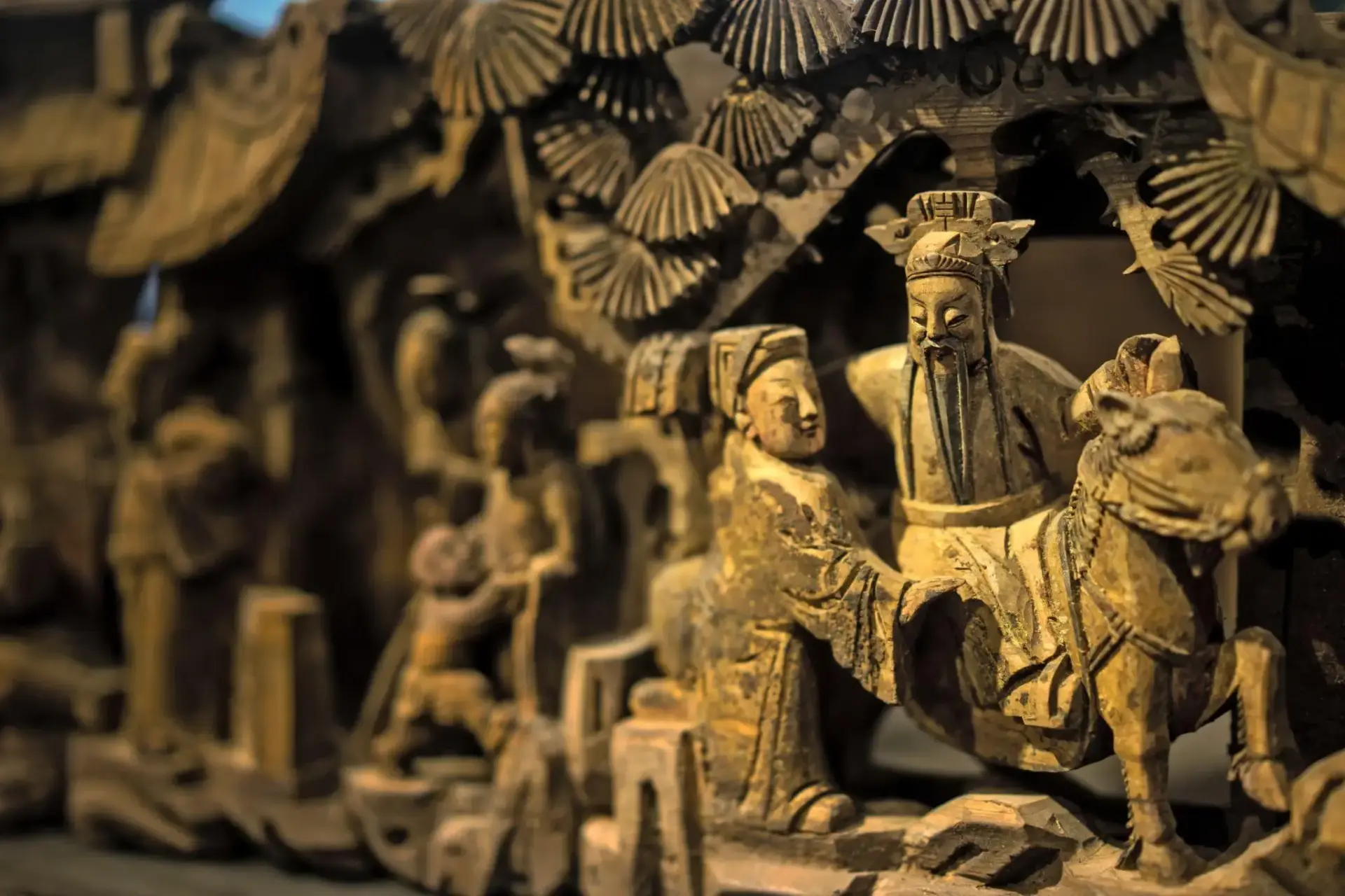 Ornate wooden sculpture depicting figures in traditional attire with intricate carvings and fine details