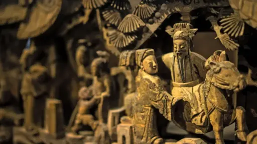 Ornate wooden sculpture depicting figures in traditional attire with intricate carvings and fine details