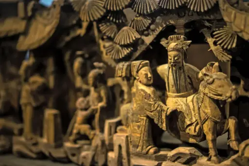 Ornate wooden sculpture depicting figures in traditional attire with intricate carvings and fine details