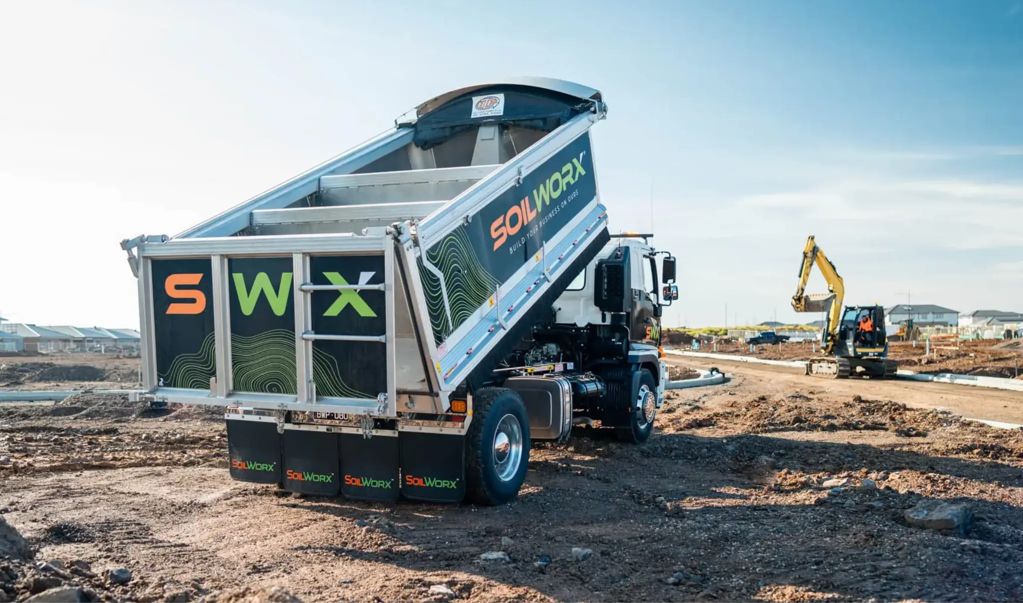 Dump truck with raised bed in construction site under clear blue sky