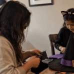 parent and child making a homemade halloween witch costume with craft supplies at a table in a cozy home setting