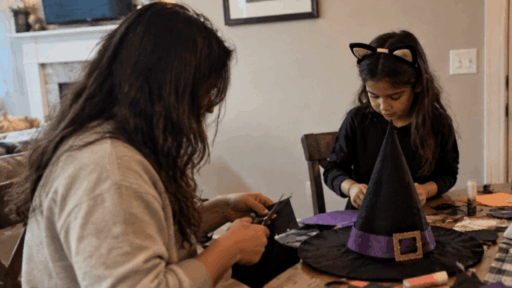 parent and child making a homemade halloween witch costume with craft supplies at a table in a cozy home setting