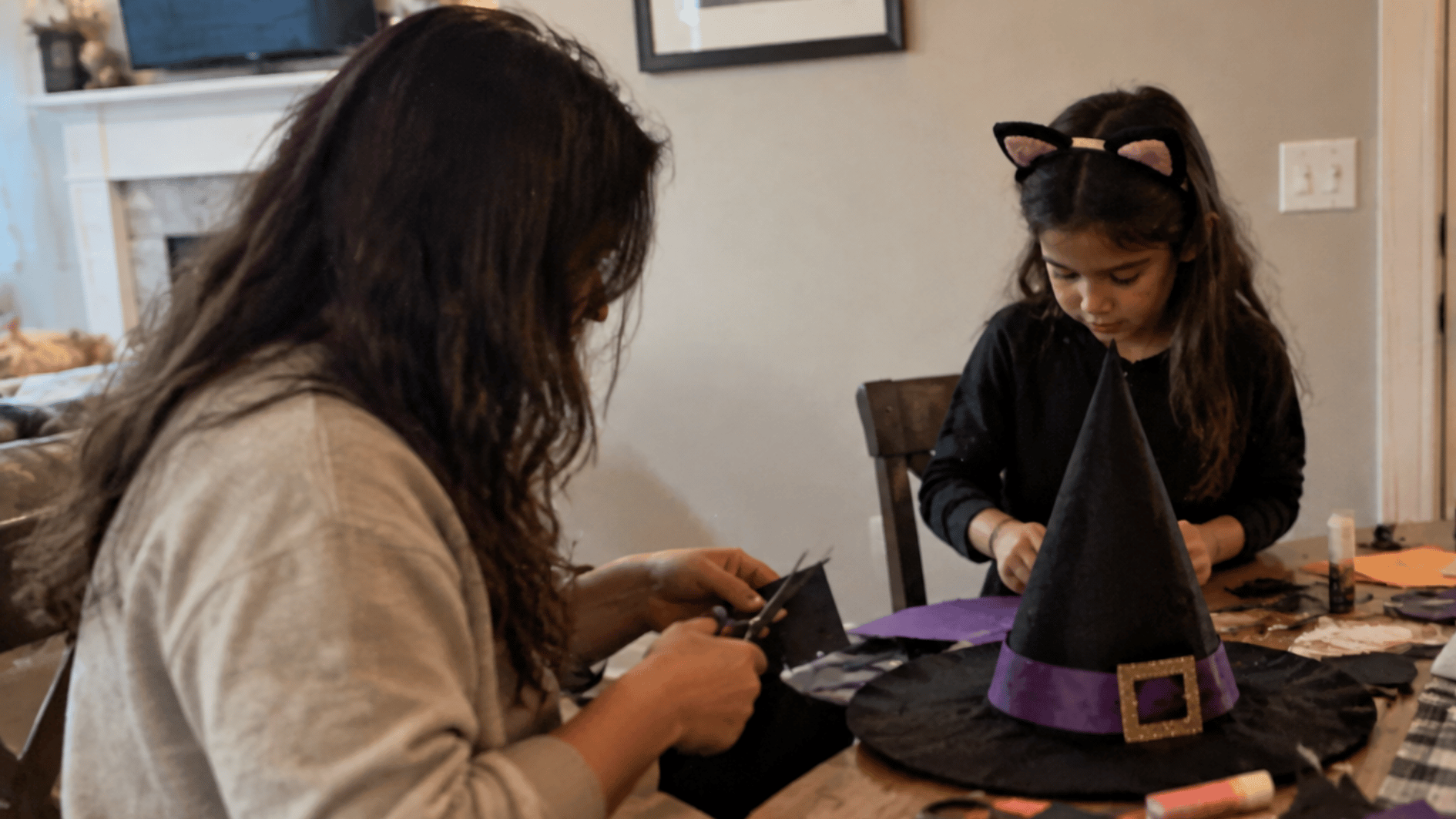 parent and child making a homemade halloween witch costume with craft supplies at a table in a cozy home setting