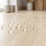 Clear marble-sized spheres on beige countertop in a bright kitchen near window and mugs