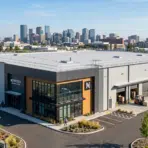 Large industrial building with loading docks in urban area, city skyline in the background