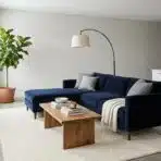 Navy blue sectional sofa in modern living room with potted plant and wooden coffee table