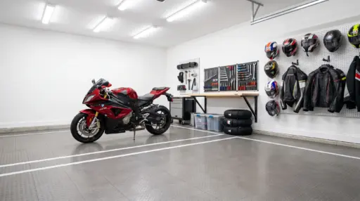 Red motorcycle in organized garage with tools, helmets, and jackets on wall-mounted pegboards