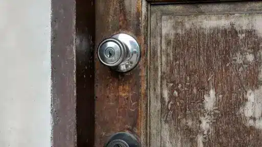 Close-up of weathered wooden door with metal doorknob and keyhole