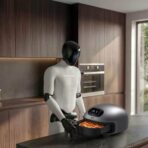 Robot operating a pizza oven in modern kitchen near large window with greenery outside