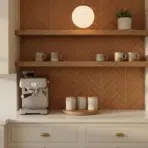 Coffee machine on kitchen counter with terracotta herringbone backsplash and wooden shelves