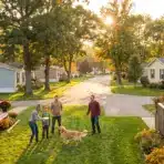 Community gathering in suburban neighborhood with families and golden retriever on sunny day