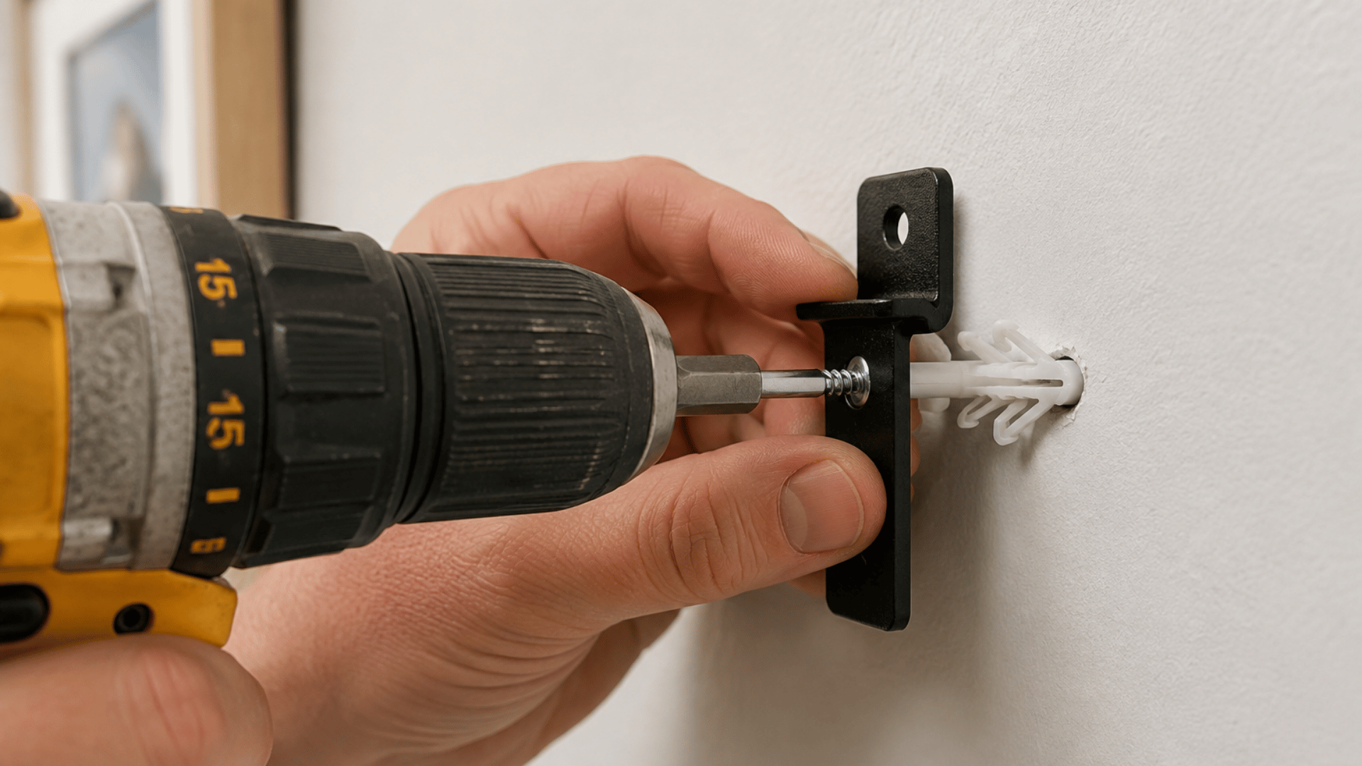 person installing a drywall anchor with a drill screw and small mounting bracket on a wall