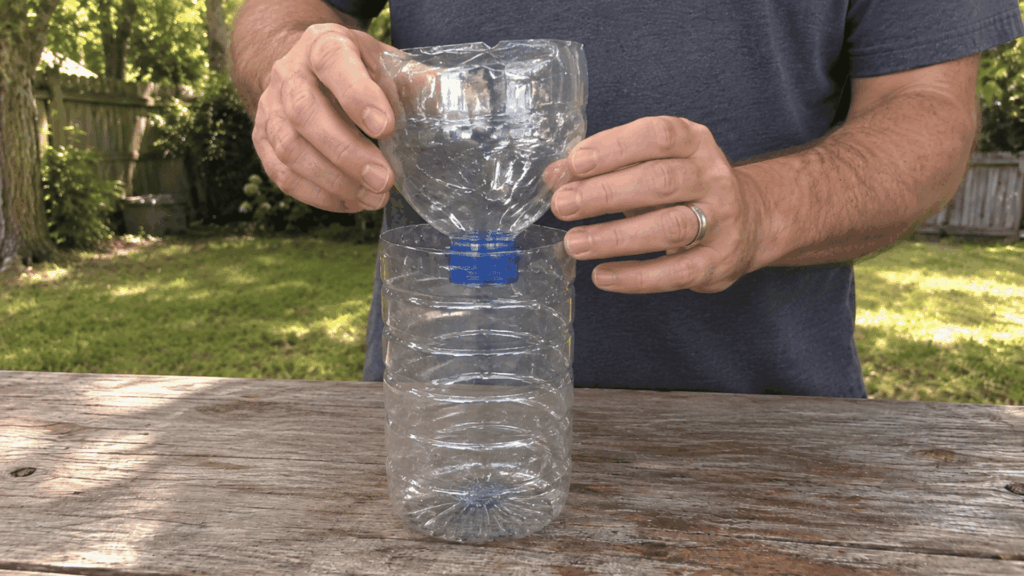placing the cut bottle top upside down inside the lower half to form the funnel entrance