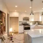 Unfinished kitchen remodel with exposed wiring and modern white cabinets under bright lighting